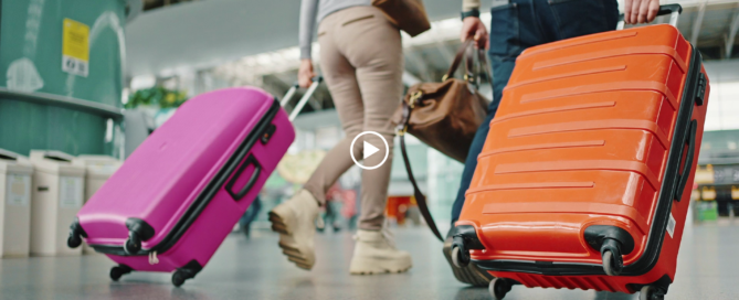 valises qui roulent dans une gare ou un aéroport qui évoquent le départ en voyage